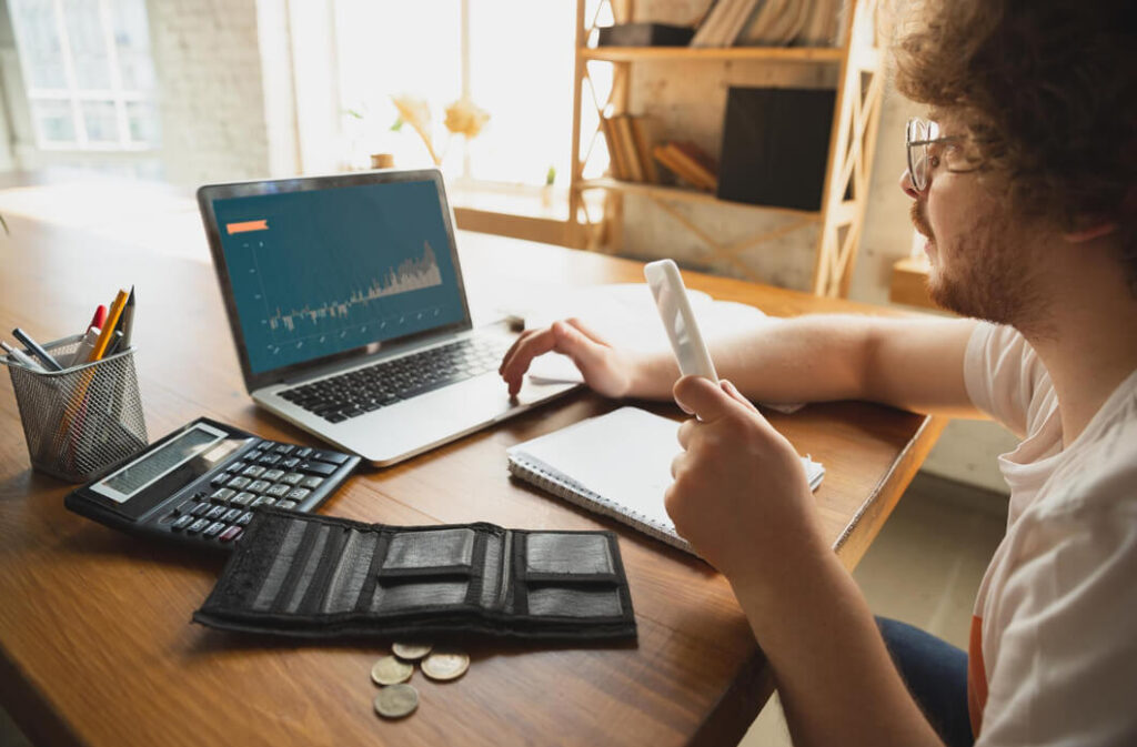 homem-branco-usando-oculos-em-escritorio-realiza-planejamento-financeiro-de-loja-virtual-com-calculadora-e-notebook