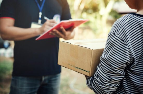 homem-de-blusa-azul-e-mulher-de-blusa-cinza-segurando-caixa-de-papelao-exemplo-entrega-programada