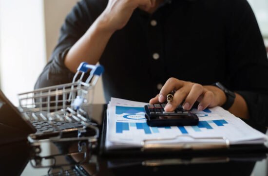 homem-de-blusa-azul-escuro-calcuando-taxa-de-conversao-no-ecommerce-com-graficos-em-papel-e-mini-carrinho-de-compras