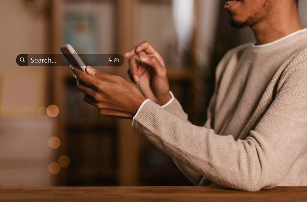 homem-de-blusa-cinza-fazendo-pesquisa-no-celular-com-mecanismos-de-busca-online