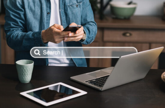 homem-de-camisa-jeans-e-branca-usando-celular-notebook-e-tablet-pesquisa-sobre-otimizacao-de-ecommerce-com-uma-barra-de-busca-no-centro-da-imagem