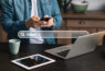 homem-de-camisa-jeans-e-branca-usando-celular-notebook-e-tablet-pesquisa-sobre-otimizacao-de-ecommerce-com-uma-barra-de-busca-no-centro-da-imagem