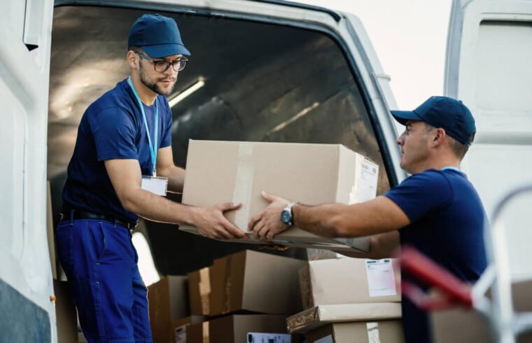 dois-homens-transportam-encomenda-em-caixa-de-papelao-para-veiculo-representando-o-calculo-de-frete