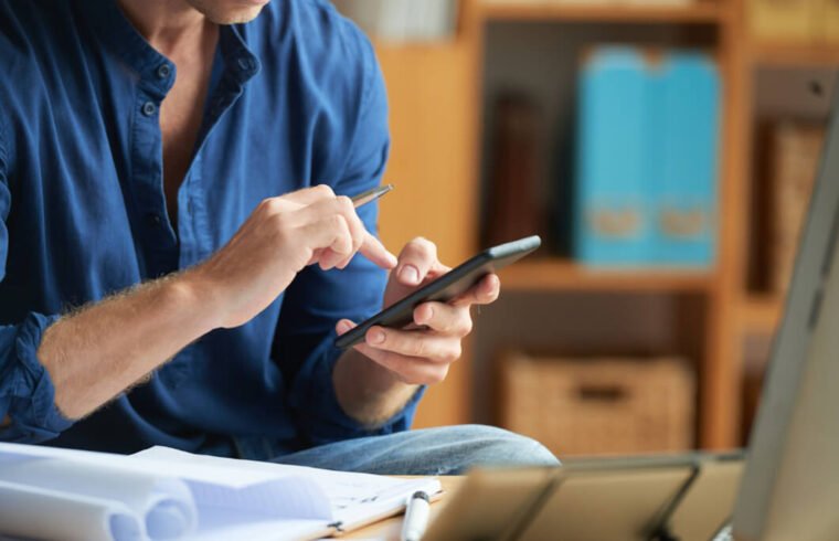 homem-de-camisa-azul-usa-aplicativo-de-loja-online-no-seu-smartphone-em-um-estoque