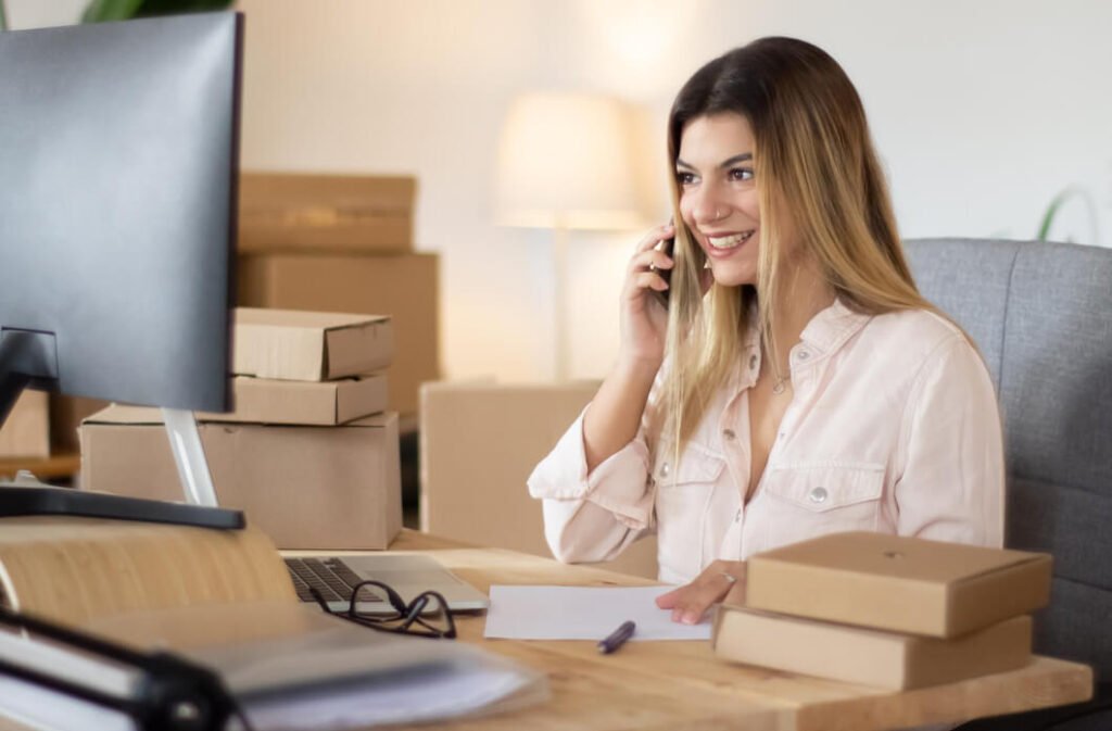 mulher-de-camisa-branca-usando-o-celular-enquando-faz-gestao-de-ecommerce-em-um-computador-de-mesa